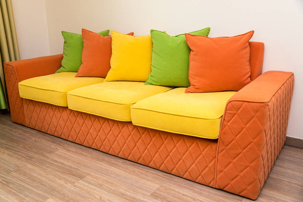 un colorato divano giallo-arancio con cuscini verdi, gialli e arancioni
 - Foto, immagini