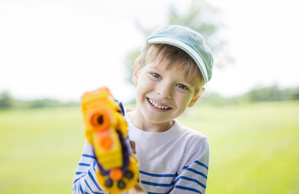 Happy young boy with toy weapon  - Фото, зображення