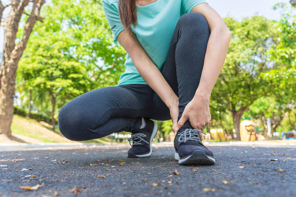 Giovane donna ha dolore al piede mentre corre nel parco. - Foto, immagini