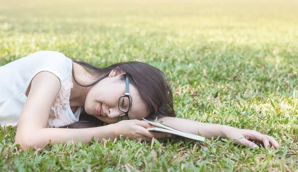 Γυναίκα ξαπλωμένη χόρτο πεδίο αφού αυτή κουρασμένος για ανάγνωση το απόγευμα - Φωτογραφία, εικόνα