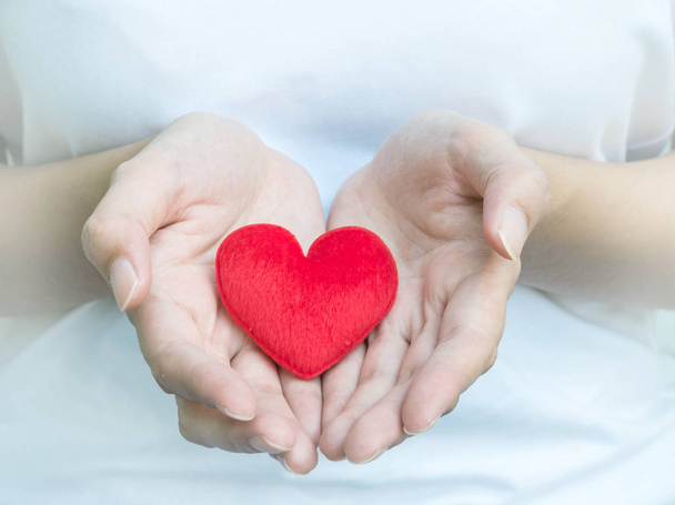 Closeup rood hart vorm stof op de handen van de vrouw - Foto, afbeelding