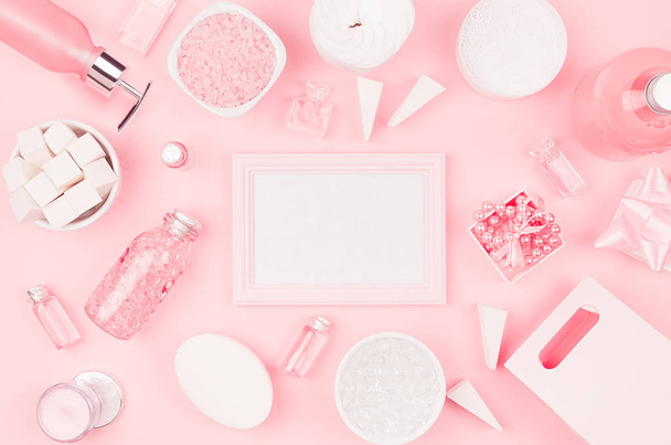 Cosmetic products and accessories in pink color - blank frame, cream, bath salt, essential oil, soap, towel, sponge, pearls, bottles, bowl on pink background. - Foto, Bild