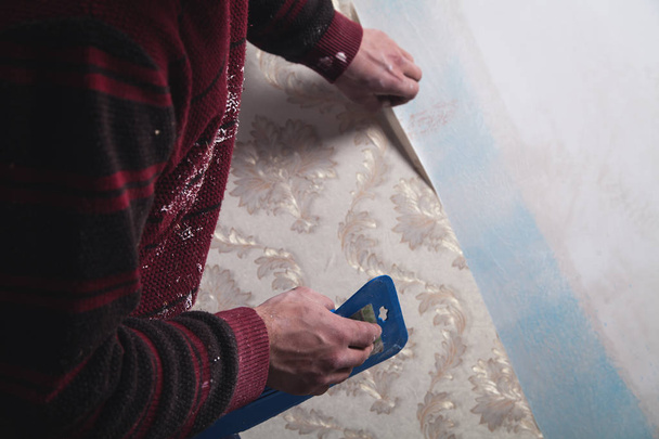 Repair the apartment. Worker glues the wallpaper to the wall.  - Photo, Image