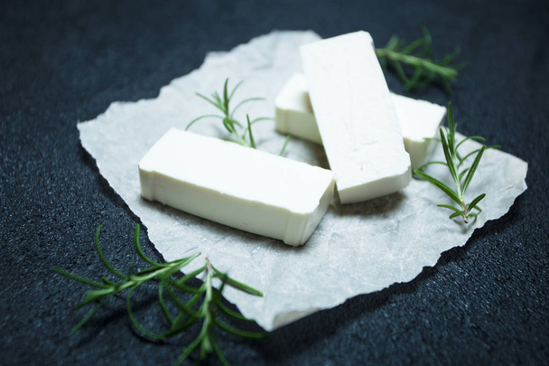 Slices of feta cheese with rosemary on parchment paper. - Fotoğraf, Görsel