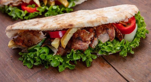 Gyros, shawarma, götürün, sokak gıda. Ahşap masa etli sandviç - Fotoğraf, Görsel