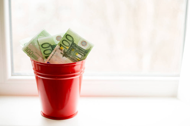 Moneybox, Euro bill in bucket on white window.light background. place for text. top view. a lot of money - Photo, Image