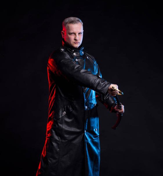 Handsome man in black leather jacket holding sword - Photo, Image