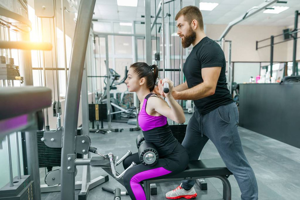Personal fitness trainer coaching and helping client woman making exercise in gym. Sport, teamwork, training, people concept. - Фото, зображення
