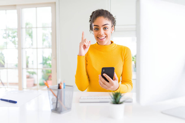Fiatal afroamerikai lány dolgozik használ a számítógép és a smartphone meglepett mutatóujjal egy ötletet vagy kérdést boldog arc, az első - Fotó, kép