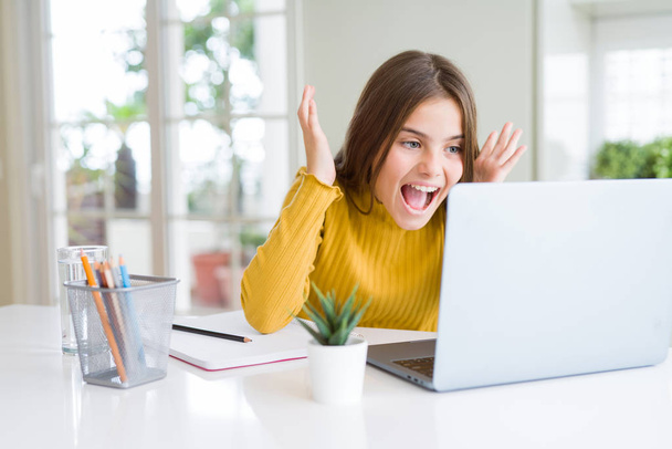 Beautiful young girl studying for school using computer laptop very happy and excited, winner expression celebrating victory screaming with big smile and raised hands - Φωτογραφία, εικόνα