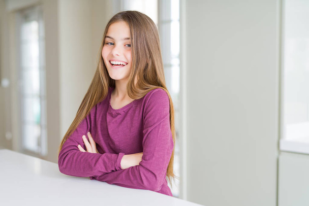 Mooi jong meisje jongen op witte tabel blij gezicht lachend met gekruiste armen kijken naar de camera. Positief persoon. - Foto, afbeelding