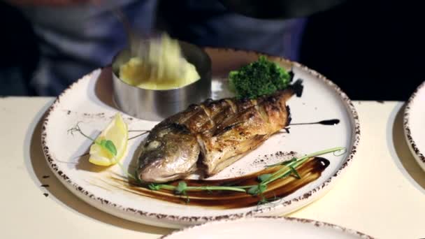 Dorado vis op een bord. Chef-koks handtekening schotel op een plaat met citroen en kruiden - Video