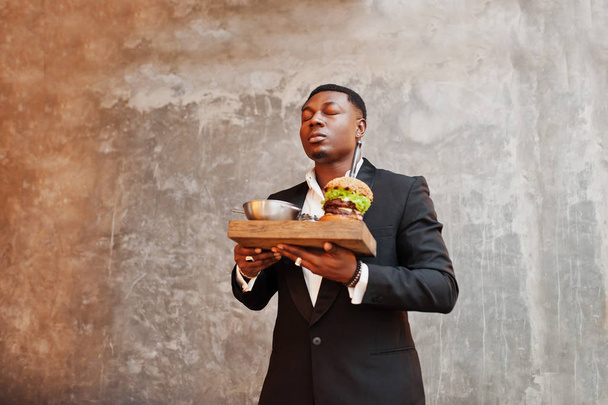 Respectable young african american man in black suit hold tray w - Foto, afbeelding