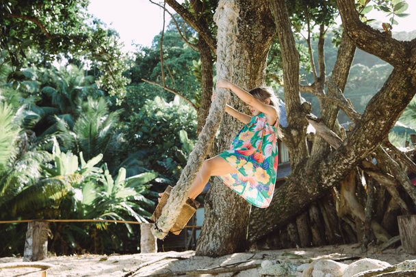 adorabile bambina sull'altalena sulla spiaggia tropicale
 - Foto, immagini