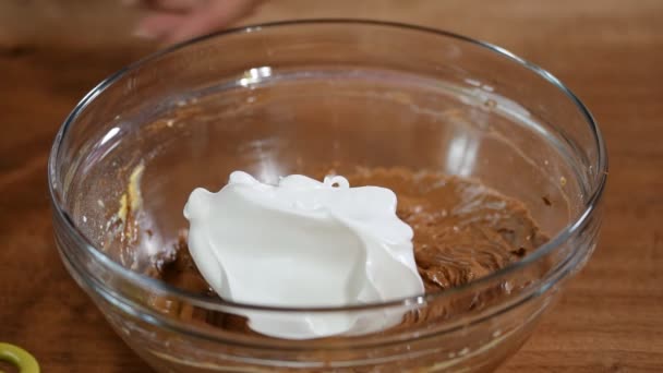 Felvert tojásfehérjével a csokoládés tészta. Folyamatos keverés közben a tojásfehérjét és a csokoládé torta tésztát - Felvétel, videó