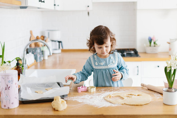 Little girl preparing easter cookies at the kitchen. - Zdjęcie, obraz
