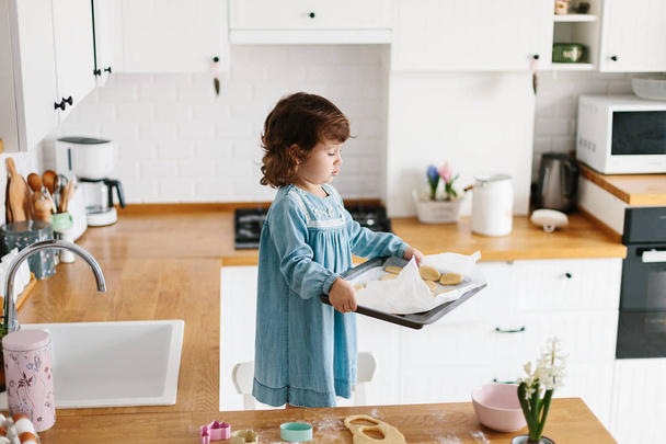 Little girl preparing easter cookies at the kitchen. - Fotó, kép