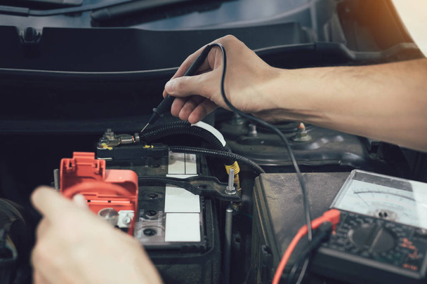 Close-up auto monteur is het gebruik van de auto batterijmeter voor het meten van  - Foto, afbeelding