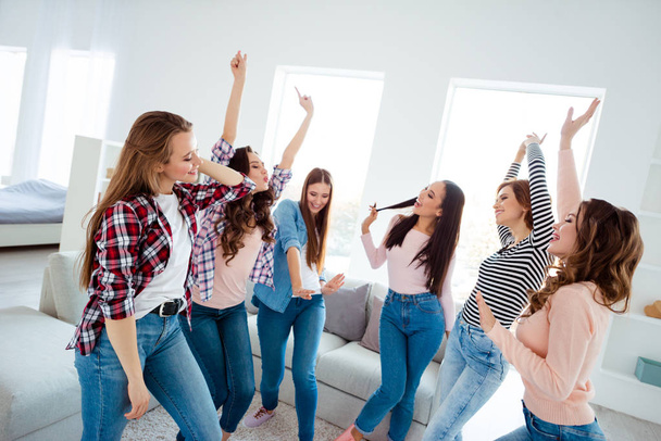 Nice shine graceful charming attractive cheerful cheery glad careless carefree girls wearing trendy casual clothes raising hands up rejoicing in light white interior room house indoors - Foto, Bild