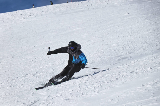 Um esquiador do sexo masculino esquiando downhill em Chopok, Eslováquia. Esculpir posição. Vira à esquerda. Freeride. Posição difícil. Casaco preto e cinzento. Corrida oficial. Prepare-se para o Campeonato
 - Foto, Imagem