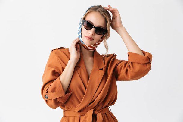 Beautiful young woman wearing silk stylish scarf posing isolated over white wall background wearing sunglasses. - Фото, изображение