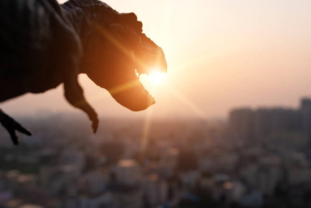 silhouette du tyrannosaure et des bâtiments au coucher du soleil
 - Photo, image