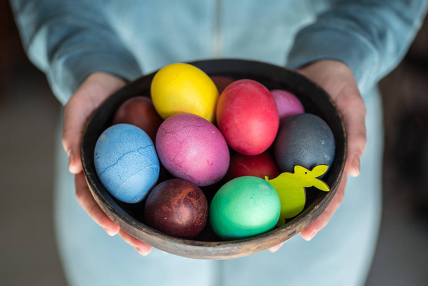 Colorful Easter eggs in bowl in woman's hands.  - Фото, изображение