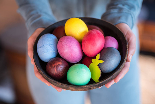 Colorful Easter eggs in bowl in woman's hands.  - 写真・画像