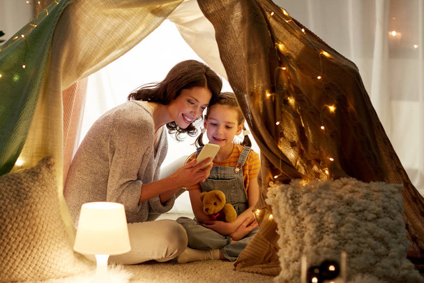happy family with smartphone in kids tent at home - Photo, image