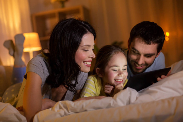 family with tablet pc in bed at night at home - Foto, Bild