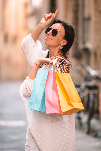 Młoda dziewczyna z torbami na zakupy na wąskiej ulicy w Europie. - Zdjęcie, obraz