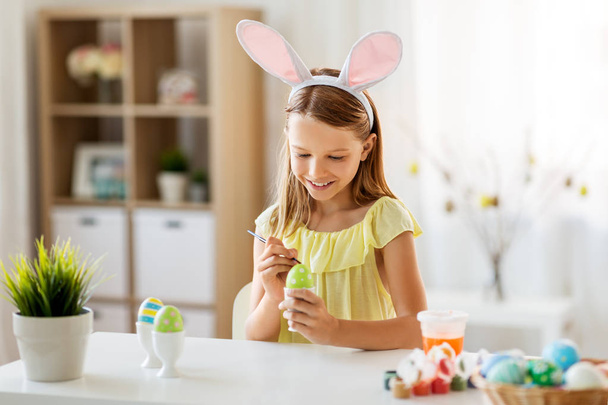 happy girl coloring easter eggs at home - Fotó, kép