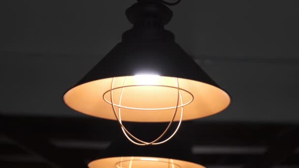 暖かい電気光源が天井の上に固定されている黒と暗い背景にオレンジ塗装装飾的なランプから. - 映像、動画
