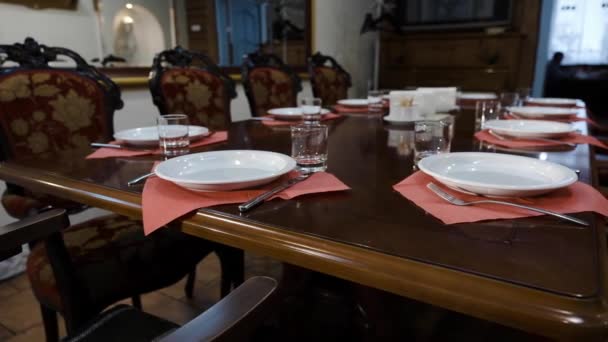 De instelling van de tabel in een prestigieus restaurant. Diepe borden en glazen bekers, vorken op een chique gepolijst houten tafel van een prestigieus restaurant. - Video