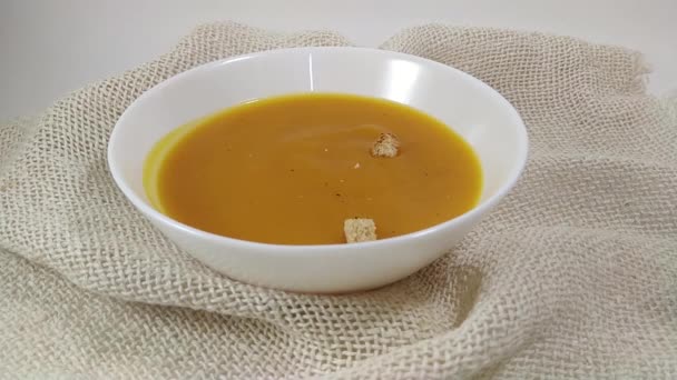 Sopa de calabaza cremosa y chuks duros cayendo en plato blanco
 - Metraje, vídeo