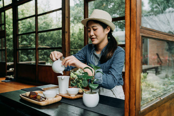 woman with hat hands pouring teapot - Fotó, kép