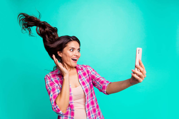 Close up photo beautiful she her lady hairstyle flight look smart phone unbelievable make take selfies wearing casual plaid checkered pink shirt outfit isolated teal bright vivid background - Foto, afbeelding