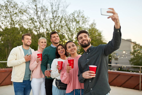 friends with drinks taking selfie at rooftop party - Foto, Bild