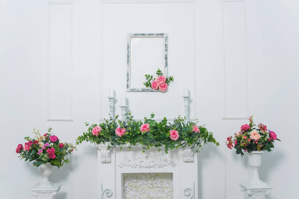 Bouquet of pink peonies. Flowers in white vase. Room decor plants. Stucco work on the white walls. Spring photo zone. Vase on column. Fireplace decorated with flowers. White candle. - Фото, изображение