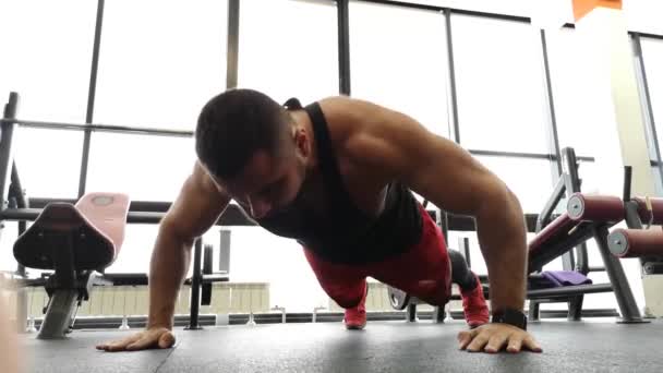 RUSSIA, TOGLIATTY - FEBRUARY 23, 2019: Young sports man performs pushups in the gym. The athlete is engaged in fitness - 映像、動画