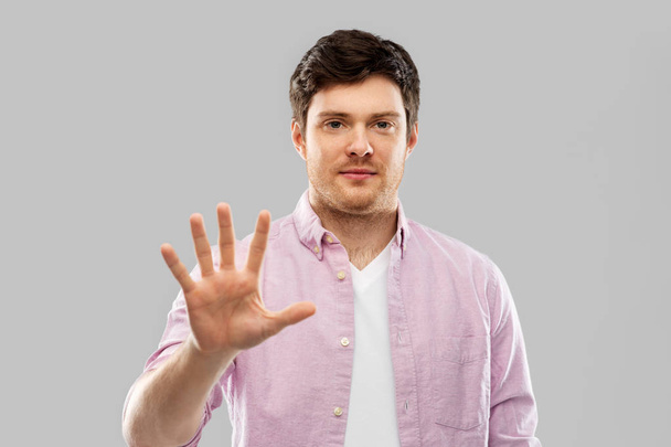 young man showing five fingers over grey - Photo, image