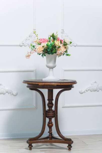 Bouquet of roses. Flowers in white vase. Room decor plants. Stucco work on the white walls. Spring photo zone. Wooden vintage table. - 写真・画像
