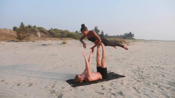 Fit sportieve paar beoefenen van acro yoga met partner samen aan het zandstrand. - Video