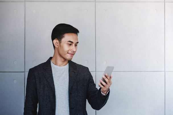 Портрет молодого счастливого бизнесмена с помощью смартфона. Standing b
 - Фото, изображение