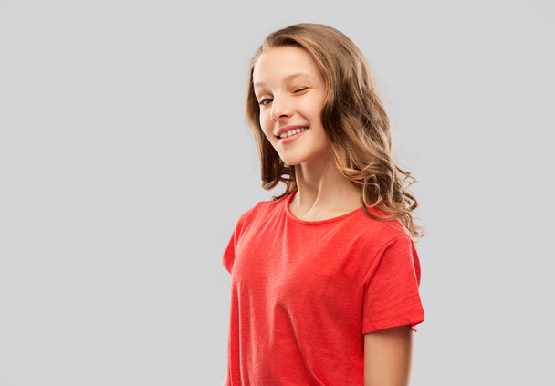 smiling teenage girl in red t-shirt winking - Photo, image