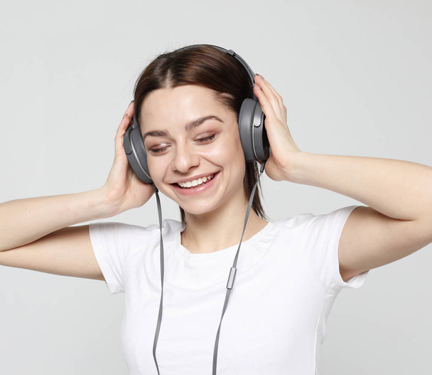 Beautiful young woman listening to music in headphones   - Foto, afbeelding