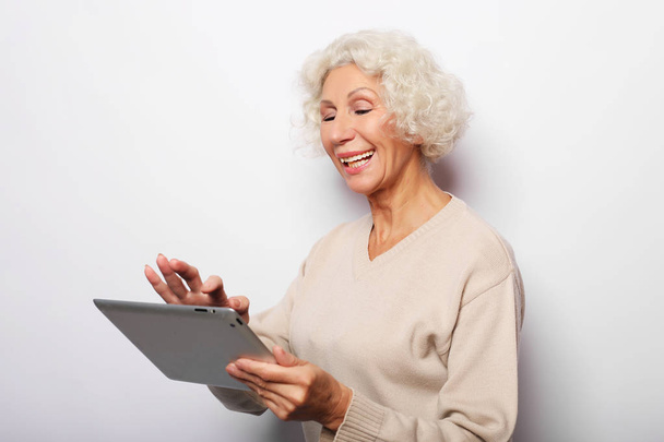 Gelukkig volwassen vrouw met behulp van een tablet, communiceert met kinderen en kleinkinderen - Foto, afbeelding