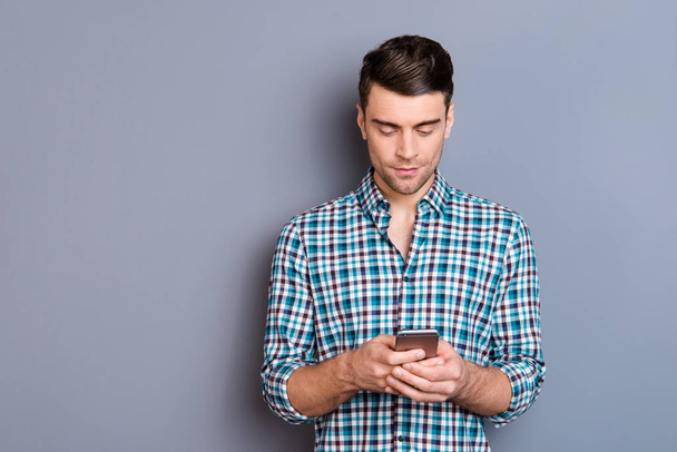 Close up photo attractive amazing he him his man arms hands telephone smart phone perfect hairdo styling look interest read news wearing casual plaid checkered shirt outfit isolated grey background - Photo, Image