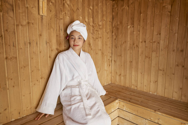 Bornoz ve havlu Sauna güzellik spa olarak vücut tedavisi alan başında Asyalı genç kadın portresi  - Fotoğraf, Görsel