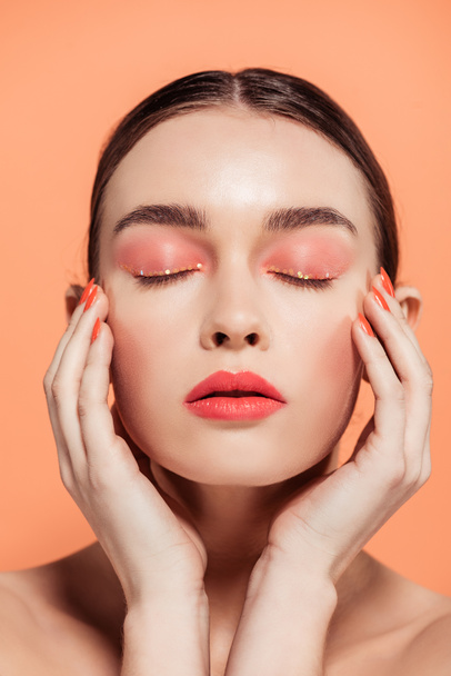 beautiful stylish young woman posing with eyes closed isolated on coral - 写真・画像